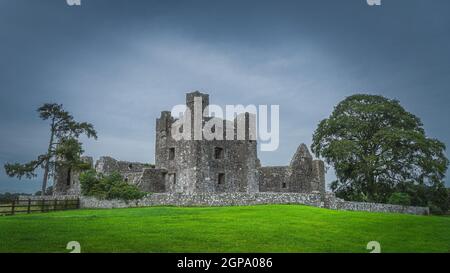 De belles ruines anciennes de l'abbaye chrétienne de Bective du XIIe siècle avec des arbres verts, des pâturages et un ciel sombre de moody en arrière-plan, comté de Meath, Irlande Banque D'Images