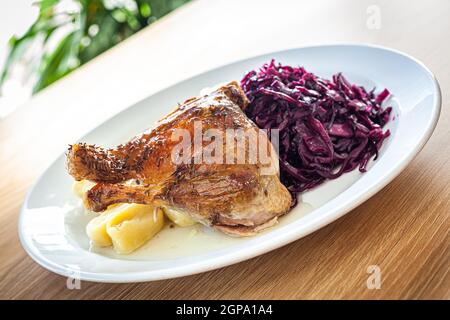 Plats cuits sur une assiette blanche - cuisse de canard rôtie, chou rouge, boulettes de pommes de terre. Banque D'Images