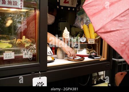 Nozawa onsen, Nagano, Japon, 2021-26-09 , femme âgée qui achète de la nourriture dans un marché de rue à Nozawaonsen Banque D'Images