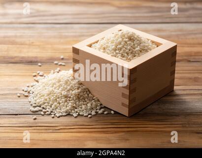 Riz gluant dans un masu (boîte en bois) placé sur un fond en bois Banque D'Images