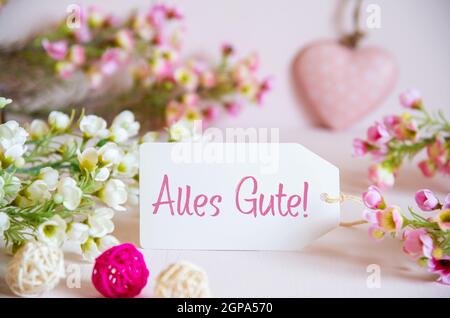 Étiquette avec texte allemand Alles Gute signifie Cordialement. Fleurs roses et blanches avec coeur décoratif. Banque D'Images