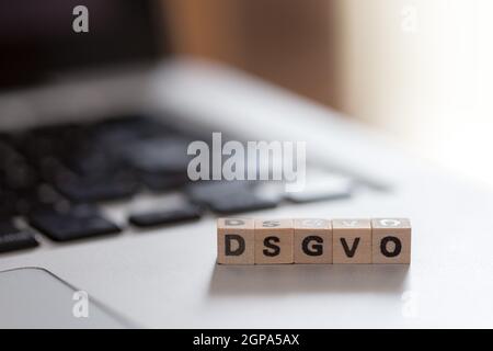 Cubes en bois avec les lettres "DGSVO Datenschutzgrundverordnung" pour se trouvent sur un ordinateur portable Banque D'Images