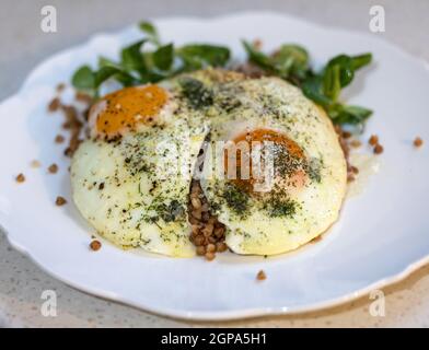 Œuf frit avec sarrasin et arugula sur une assiette blanche Banque D'Images