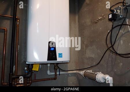 Chauffe-eau sans réservoir Navien installé comme remplacement efficace d'une ancienne chaudière et d'un ancien système de réservoir d'eau. Banque D'Images