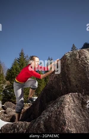 Jeune femme grimpeur mettant des chaussures d'escalade avant d'escalader un rocher en plein air, dans les Alpes suisses Banque D'Images