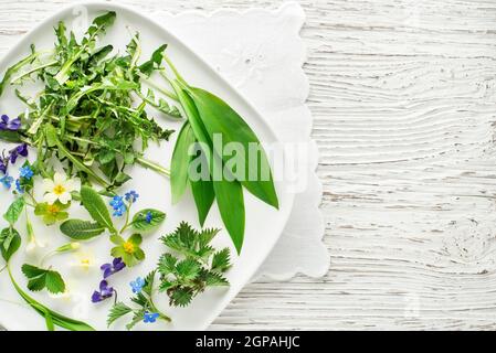 Ingrédients alimentaires de plantes de printemps sains. Pissenlit, ail sauvage, fleurs et ortie sur l'assiette Banque D'Images