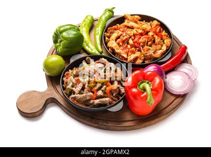 Fajita savoureuse avec des légumes dans des poêles à frire sur fond blanc Banque D'Images