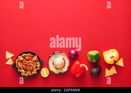 Composition avec de savoureux fajita, légumes et chapeau de sombrero sur fond rouge Banque D'Images