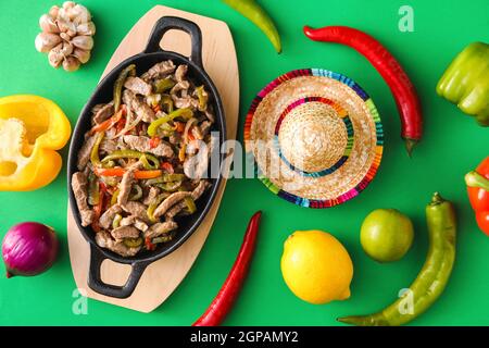 Composition avec de délicieux fajita, légumes et chapeau de sombrero sur fond de couleur Banque D'Images