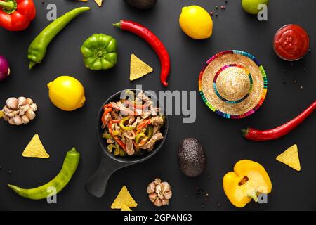 Composition avec de délicieux fajita, légumes et chapeau de sombrero sur fond sombre Banque D'Images