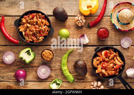 Composition avec de savoureux fajita, légumes, sauce et chapeau de sombrero sur fond de bois Banque D'Images