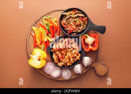 Poêles à frire avec de savoureux fajita et légumes sur fond de couleur Banque D'Images