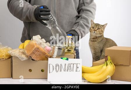 l'homme recueille de la nourriture, des fruits et des choses dans une boîte en carton pour aider les nécessiteux et les pauvres, aider et le concept de bénévolat Banque D'Images