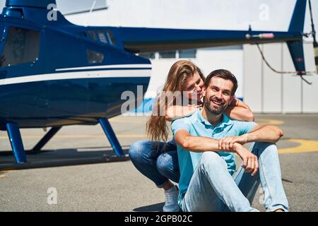 Couple romantique assis sur la piste d'atterrissage en hélicoptère Banque D'Images