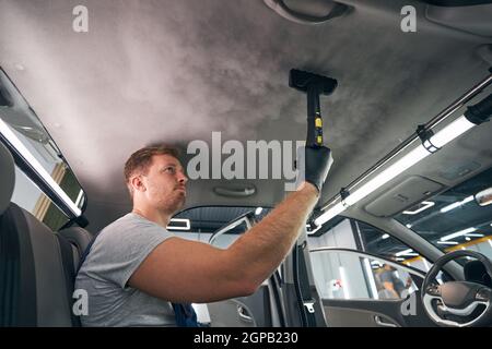 Employé du service après-vente utilisant un nettoyant à vapeur pour cabine automobile. Stérilisation à la vapeur Banque D'Images