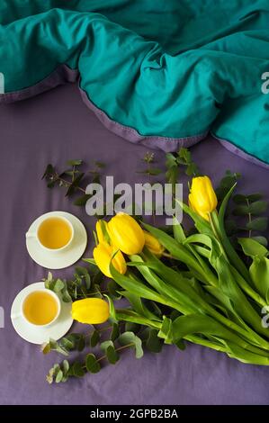 Tulipes jaunes et deux tasses de thé au lit, matin Banque D'Images