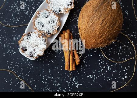 Muffins à la noix de coco avec le chocolat et cannelle sur un fond noir et de noix de coco entière Banque D'Images