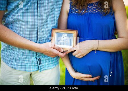 Le mari et sa femme enceinte en souriant et en regardant l'échographie de la grossesse photo. Banque D'Images