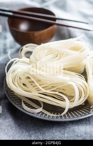 Nouilles de riz blanc séchées. Pâtes brutes. Nouilles non cuites sur l'assiette. Banque D'Images