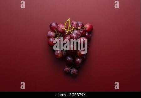 Globe rouge avec des gouttes d'eau placées sur un fond rouge foncé mat. Vue de directement au-dessus. Banque D'Images