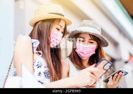 jeune femme portant un masque médical de protection du visage et regardant le téléphone portable dans la rue Banque D'Images