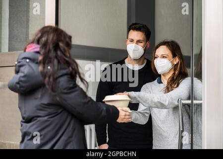 Voisin donnant de l'aide alimentaire de secours dans le masque facial Banque D'Images