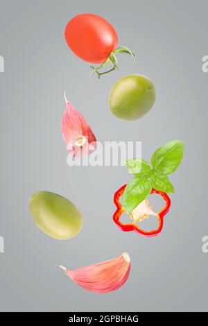 Légumes isolés. Mélange de tomates, d'olives vertes, de basilic, de poivron et d'ail tombant isolat sur le gris ultime avec le chemin d'écrêtage comme paquet d Banque D'Images