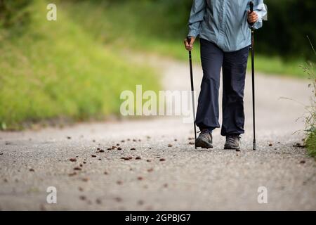 Personne âgée qui reste en forme en faisant un exercice cardio quotidien, en allant pour une marche de puissance rapide avec des bâtons Banque D'Images