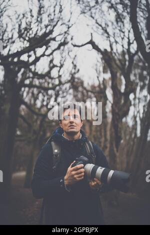 Jeune homme consacrant du temps à son passe-temps préféré : la photographie - prendre des photos à l'extérieur avec son appareil photo numérique/reflex numérique Banque D'Images