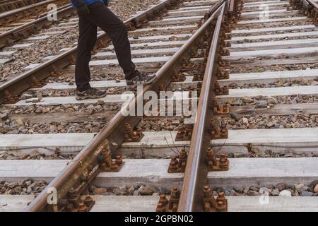 L'homme traverse les voies de chemin de fer. Concept de croisement dangereux. Banque D'Images