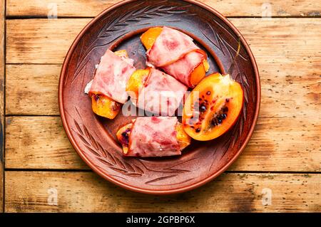 Morceaux de Tamarillo emballés et cuits avec du jambon et du bacon Banque D'Images