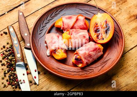 Morceaux de Tamarillo emballés et cuits avec du jambon et du bacon Banque D'Images