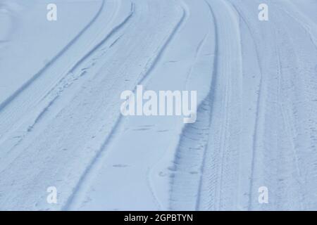 Traces de pneus de voitures dans la neige fraîche. Traces de roues sur la neige des voitures. Tracé automobile sur route d'hiver. Route de campagne recouverte de neige. Transport en hiver. Banque D'Images