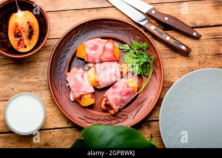 Morceaux de Tamarillo emballés et cuits avec du jambon et du bacon Banque D'Images