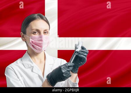 Une jeune fille prépare la vaccination contre le drapeau du Danemark. Concept de vaccination Danemark. Banque D'Images
