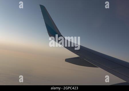 Dans l'air, vue de l'aile de l'avion avec l'horizon du ciel bleu foncé et nuages arrière-plan en heure de lever du soleil, vue de la fenêtre de l'avion Banque D'Images