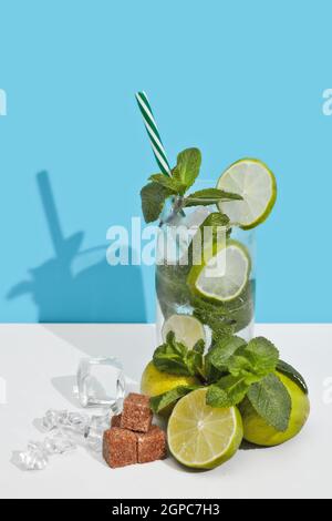 Mojito cocktail au citron vert, feuilles de menthe et morceaux de sucre sur fond bleu blanc double avec ombre. Banque D'Images