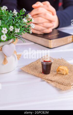 Jeune femme priant et prenant la communion - le vin et les symboles du pain de Jésus Christ sang et corps avec la Sainte Bible. Pâque de Pâques et Seigneur su Banque D'Images