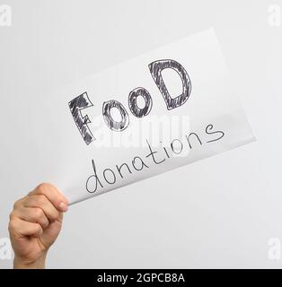 main féminine tient une feuille de papier blanche avec l'inscription dons alimentaires, gros plan Banque D'Images