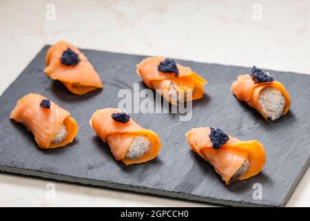 rouleaux de saumon fumé remplis de fromage à la crème et de caviar noir Banque D'Images