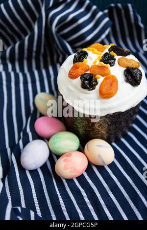 Les œufs de Pâques décorés d'aquarelles et de gâteau de Pâques sont placés sur un tablier bleu rayé. Concept de vacances religieuses de Pâques Banque D'Images