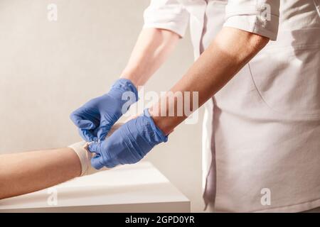 Le médecin impose un bandage élastique au poignet du patient. Réadaptation après la pluie. Banque D'Images