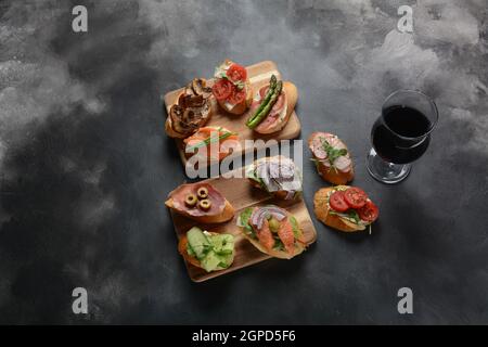 Brushetta ou des tapas espagnoles traditionnelles. Hors-d'antipasti italiens avec des collations. Variété de petits sandwichs au jambon, tomates cerises, du saumon Banque D'Images