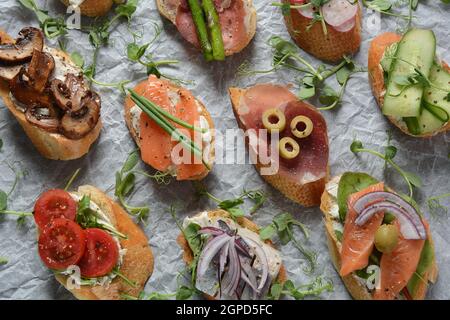 Brushetta ou des tapas espagnoles traditionnelles. Hors-d'antipasti italiens avec des collations. Variété de petits sandwichs au jambon, tomates cerises, du saumon Banque D'Images