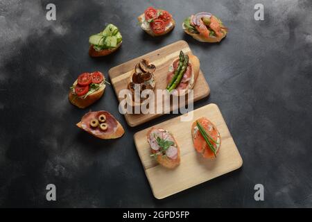 Brushetta ou des tapas espagnoles traditionnelles. Hors-d'antipasti italiens avec des collations. Variété de petits sandwichs au jambon, tomates cerises, du saumon Banque D'Images