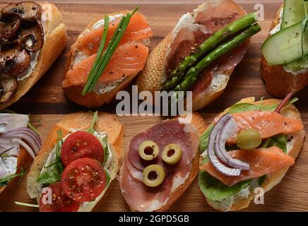 Brushetta ou des tapas espagnoles traditionnelles. Hors-d'antipasti italiens avec des collations. Variété de petits sandwichs au jambon, tomates cerises, du saumon Banque D'Images