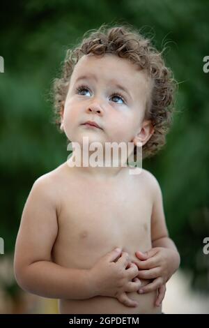 Beau Bébé avec des cheveux bouclés dans le jardin sans t-shirt Banque D'Images