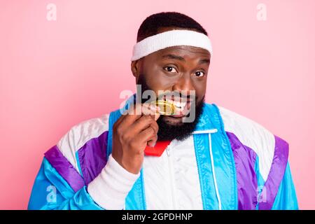 Photo de cool drôle noir peau homme porter bleu costume bandeau mordant or médaille sourire isolé couleur rose fond Banque D'Images