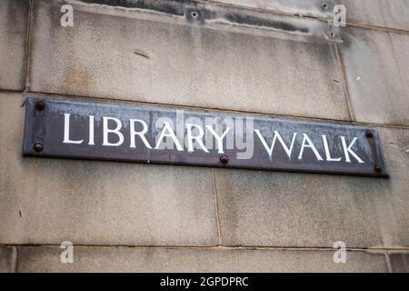 Panneau de la bibliothèque sur le vieux mur en pierre. Panneau métallique avec texte blanc. Banque D'Images