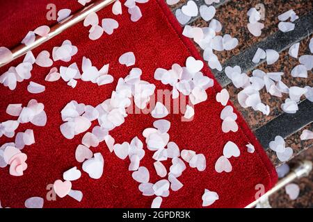 Magnifique mariage confetti amour coeur forme Scatter sur le tapis rouge après avoir été jeté sur la mariée et marié pour célébrer la cérémonie de mariage. Romantique. Banque D'Images